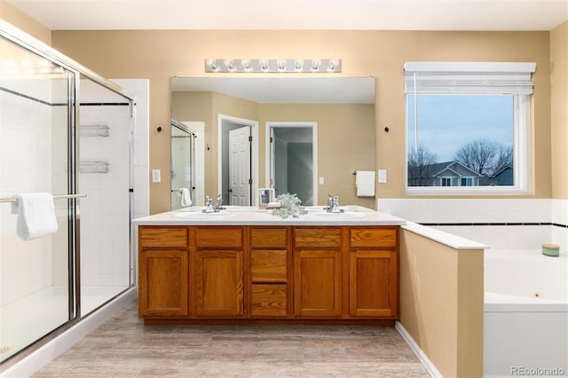 bathroom featuring double vanity, a jetted tub, a stall shower, and a sink