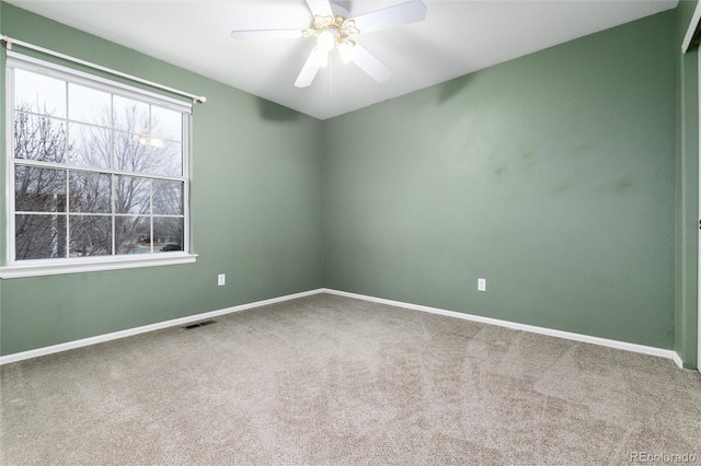 carpeted empty room featuring baseboards, visible vents, and ceiling fan