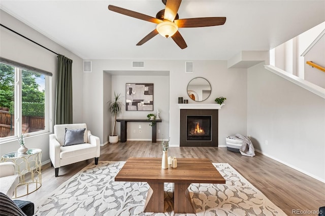 6723 Silverwind Cir, Colorado Springs, CO 80923 - living area featuring ceiling fan, wood finished floors, a tiled fireplace, and stairway