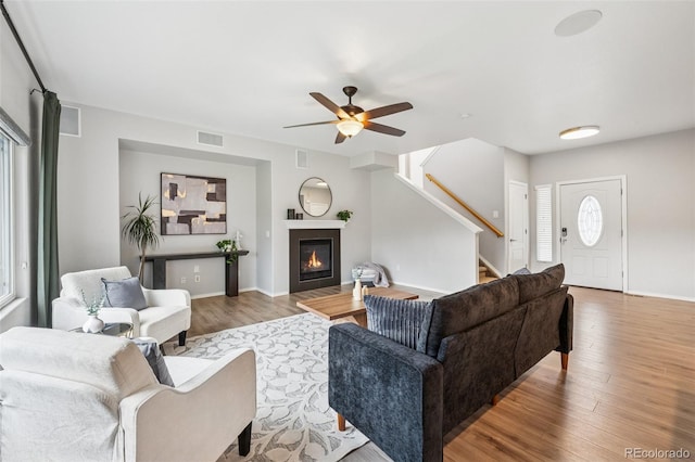 6723 Silverwind Cir, Colorado Springs, CO 80923 - living room featuring stairs, wood finished floors, ceiling fan, and a glass covered fireplace