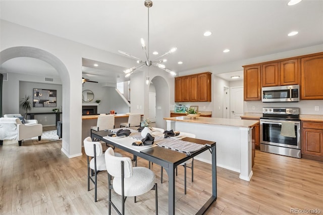 6723 Silverwind Cir, Colorado Springs, CO 80923 - dining room with arched walkways, recessed lighting, light wood finished floors, ceiling fan, and a warm lit fireplace