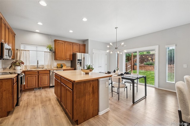 6723 Silverwind Cir, Colorado Springs, CO 80923 - kitchen featuring stainless steel appliances, light countertops, brown cabinets, a chandelier, and light wood-type flooring