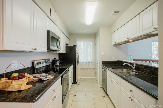 kitchen with dark stone countertops, white cabinetry, light tile patterned flooring, and stainless steel appliances