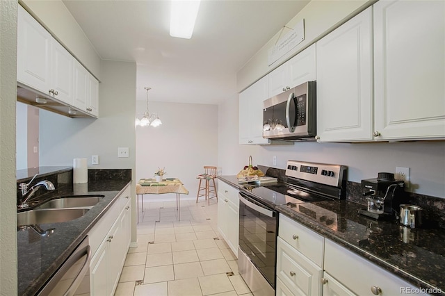 kitchen with white cabinets, light tile patterned floors, sink, dark stone countertops, and stainless steel appliances