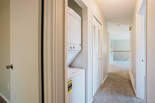 laundry room with light colored carpet and stacked washing maching and dryer