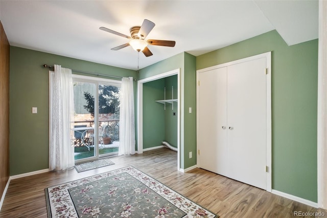 unfurnished bedroom featuring access to outside, ceiling fan, a closet, and hardwood / wood-style floors