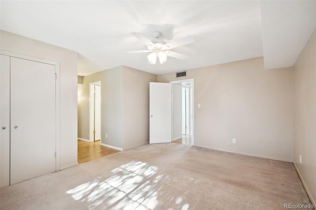 unfurnished bedroom featuring ceiling fan, light colored carpet, and a closet