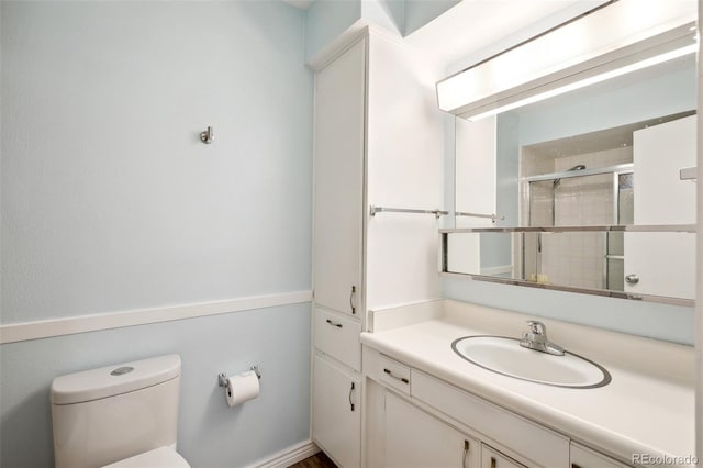 bathroom featuring toilet, a shower with door, and vanity