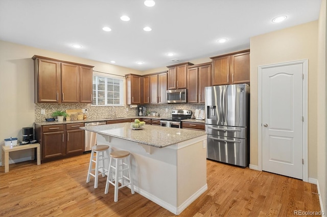 25811 E Archer Ave, Aurora, CO 80018 - kitchen featuring stainless steel appliances, light wood-type flooring, backsplash, a breakfast bar, and recessed lighting