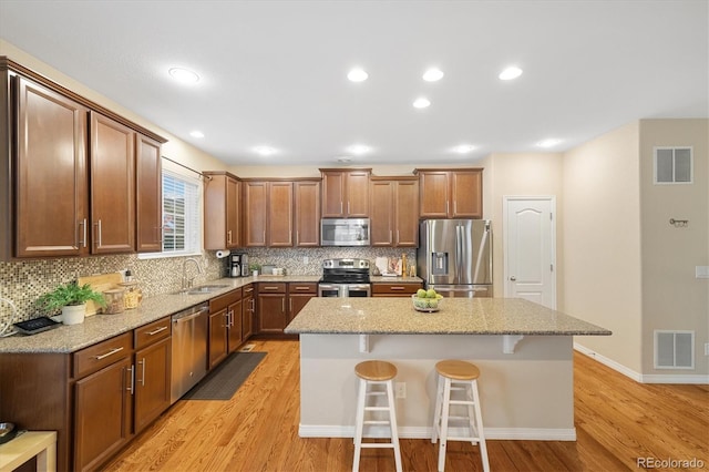 25811 E Archer Ave, Aurora, CO 80018 - kitchen with appliances with stainless steel finishes, a sink, a breakfast bar, light wood-type flooring, and recessed lighting