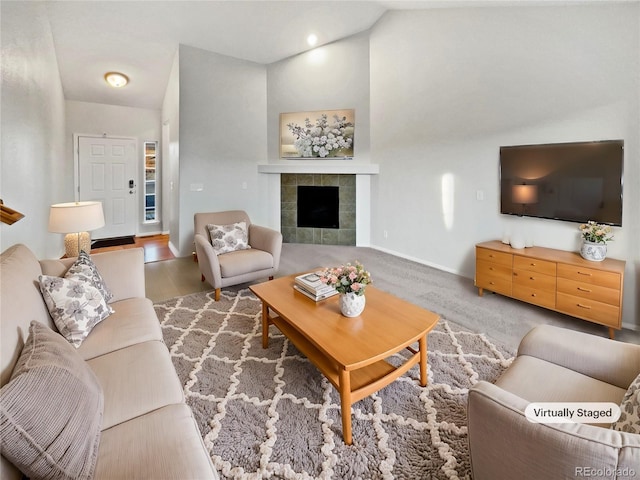 living area with a tile fireplace, lofted ceiling, baseboards, and wood finished floors