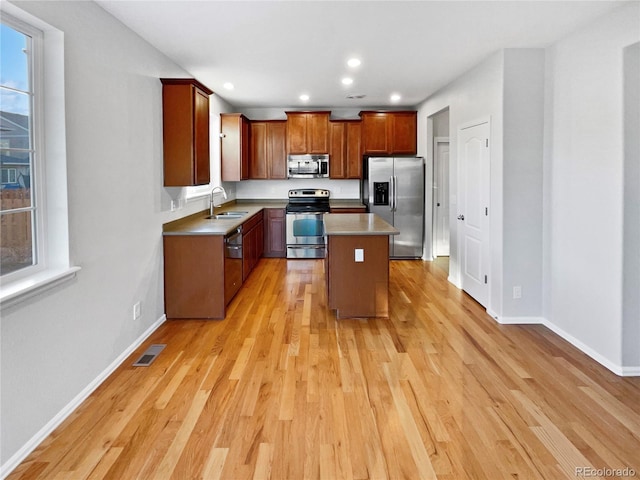 kitchen with baseboards, appliances with stainless steel finishes, light wood-type flooring, a sink, and recessed lighting