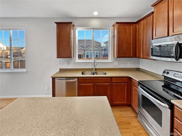 kitchen featuring light countertops, stainless steel appliances, light wood-style floors, a sink, and recessed lighting