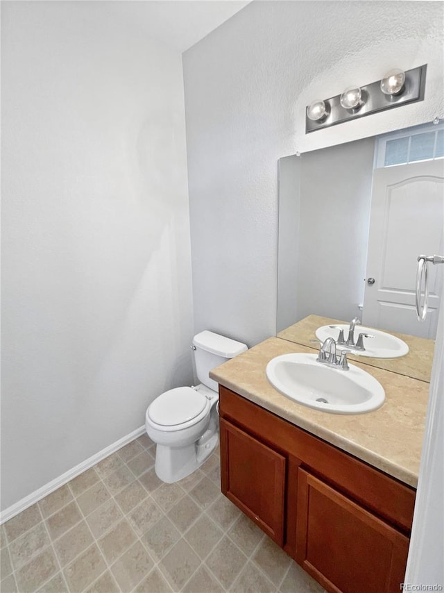 bathroom with toilet, vanity, and baseboards