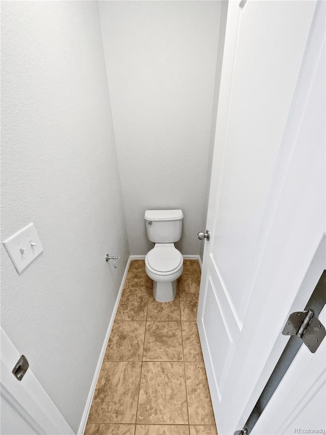 bathroom with toilet, tile patterned flooring, and baseboards