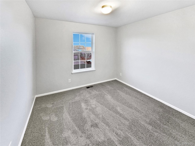 empty room with carpet floors, visible vents, and baseboards