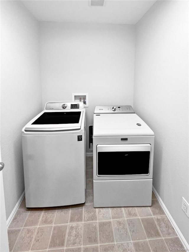 clothes washing area with laundry area, visible vents, baseboards, and independent washer and dryer