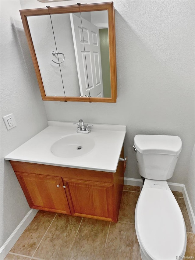 half bath featuring tile patterned flooring, vanity, toilet, and baseboards