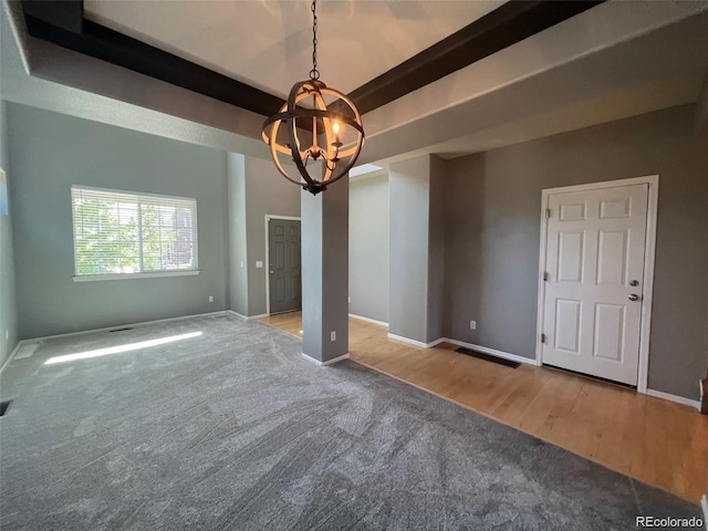 spare room with beam ceiling, light wood-type flooring, and a notable chandelier