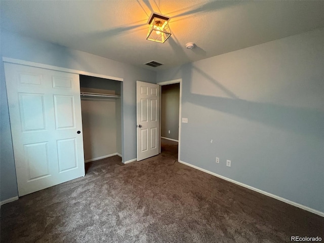 unfurnished bedroom featuring dark carpet and a closet