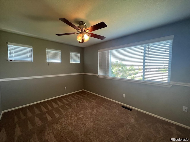 empty room with dark colored carpet and ceiling fan