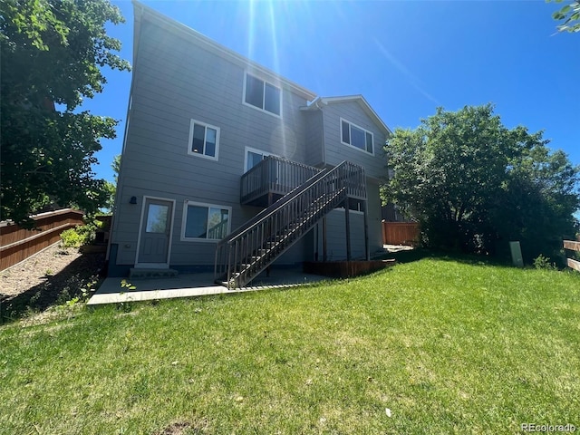 rear view of property featuring a lawn and a deck