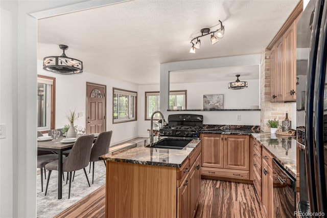 1060 S Eaton St, Lakewood, CO 80226 - kitchen with black appliances, dark stone countertops, dark wood-type flooring, decorative backsplash, and an island with sink