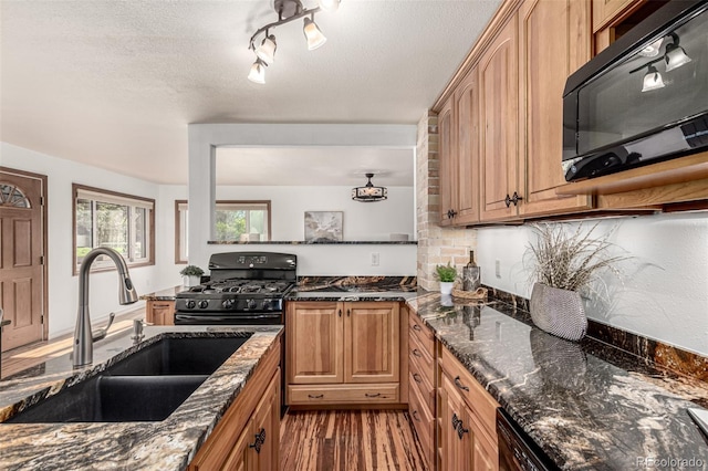 1060 S Eaton St, Lakewood, CO 80226 - kitchen with black appliances, light wood-style flooring, dark stone countertops, and a textured ceiling
