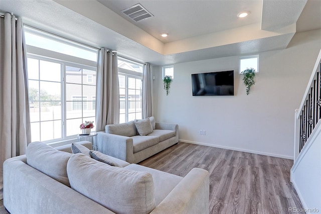 living room featuring a tray ceiling and light hardwood / wood-style floors