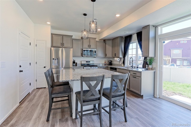 kitchen with a kitchen island, pendant lighting, light hardwood / wood-style flooring, and stainless steel appliances