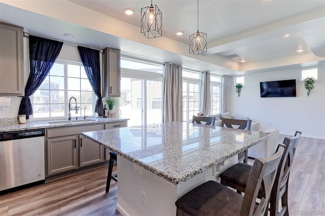 kitchen featuring pendant lighting, sink, dishwasher, a breakfast bar, and light wood-type flooring