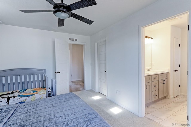 carpeted bedroom featuring ceiling fan, ensuite bath, and sink