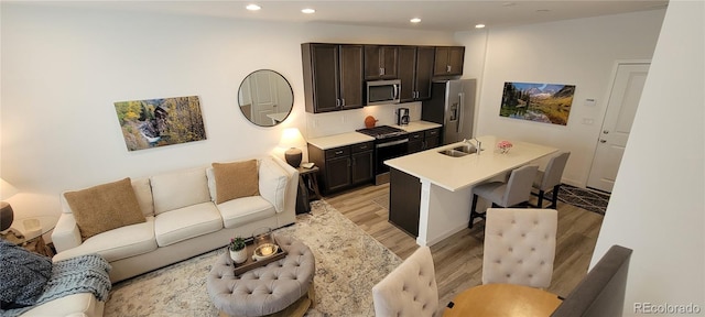 9279 Merino Ct Unit B, Littleton, CO 80125 - kitchen featuring stainless steel appliances, open floor plan, light wood finished floors, a breakfast bar, and a center island with sink