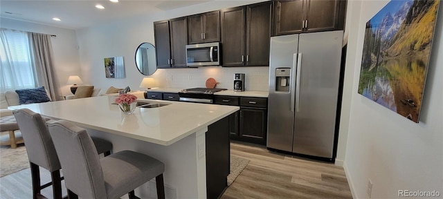 9279 Merino Ct Unit B, Littleton, CO 80125 - kitchen with appliances with stainless steel finishes, light wood-style flooring, open floor plan, backsplash, and a kitchen breakfast bar