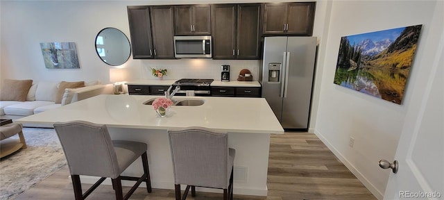 9279 Merino Ct Unit B, Littleton, CO 80125 - kitchen with stainless steel appliances, wood finished floors, light countertops, decorative backsplash, and a kitchen breakfast bar