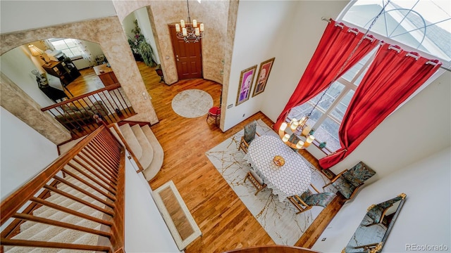 9832 N Crystal Lake Dr, Littleton, CO 80125 - living area featuring arched walkways, a towering ceiling, wood finished floors, a chandelier, and stairway