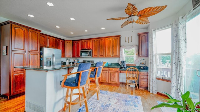 9832 N Crystal Lake Dr, Littleton, CO 80125 - kitchen with appliances with stainless steel finishes, recessed lighting, a kitchen bar, a ceiling fan, and light wood-style floors