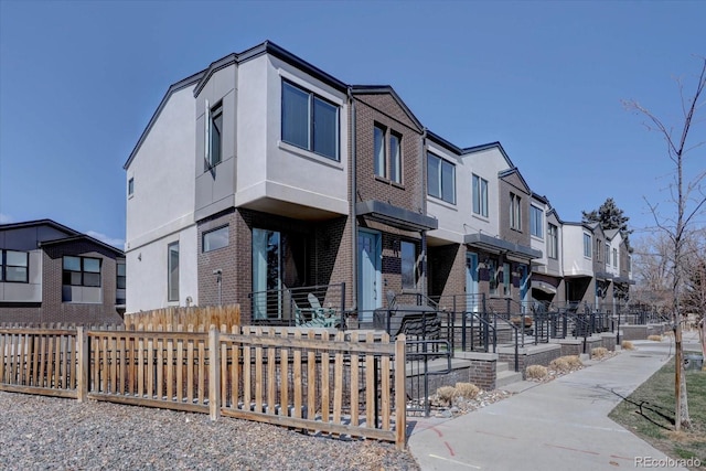 view of front facade with a fenced front yard, a residential view, brick siding, and stucco siding