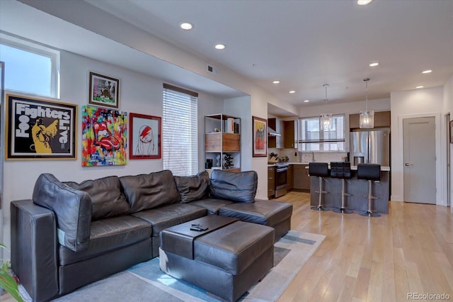 living area featuring recessed lighting, plenty of natural light, visible vents, and light wood-type flooring