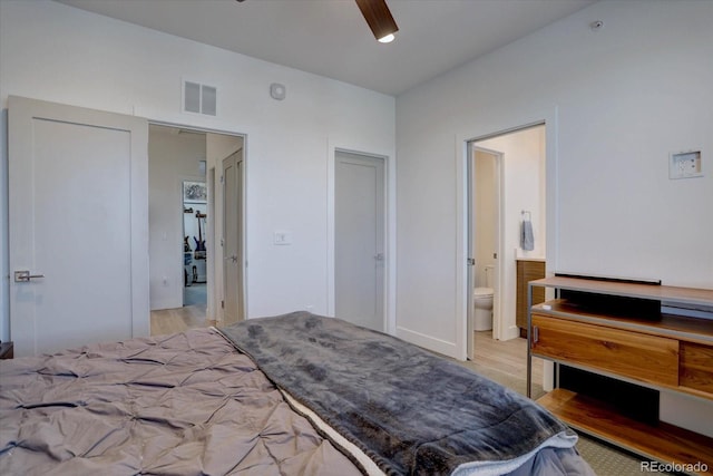 bedroom with light wood-type flooring, visible vents, and ensuite bath