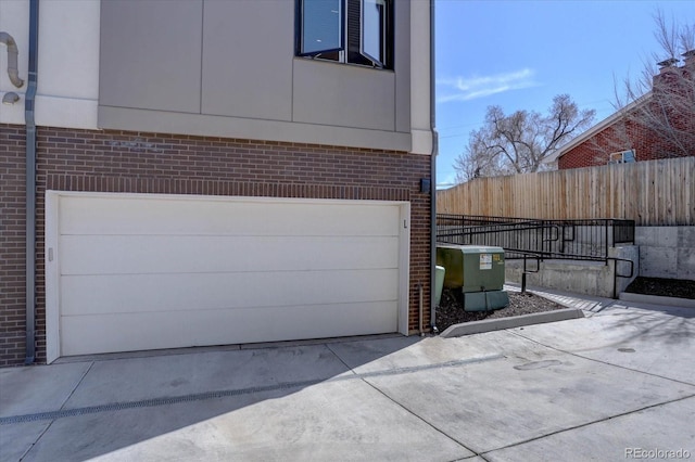 garage featuring fence and driveway