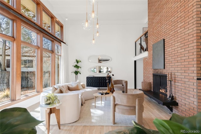 living area featuring a brick fireplace, a towering ceiling, and wood finished floors