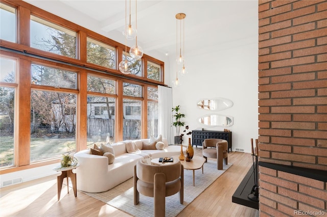 living room with beamed ceiling, plenty of natural light, light wood-style floors, and visible vents