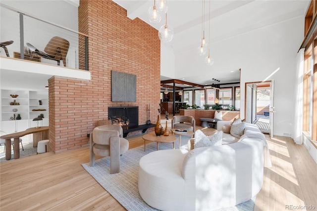 living room with beam ceiling, high vaulted ceiling, a brick fireplace, and wood finished floors