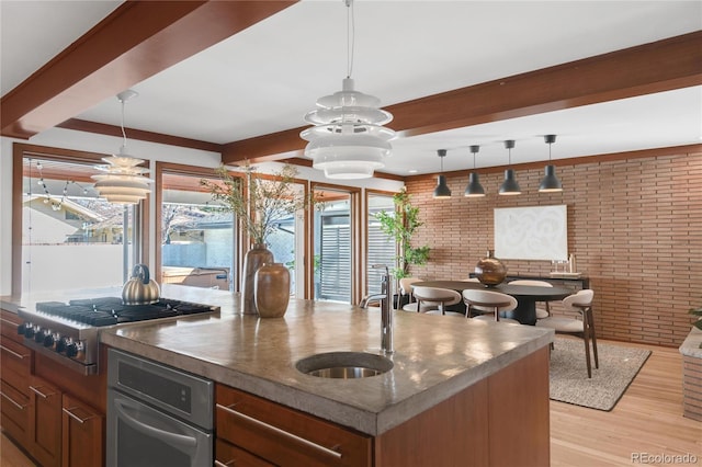 kitchen with beamed ceiling, stainless steel gas cooktop, brick wall, and a sink