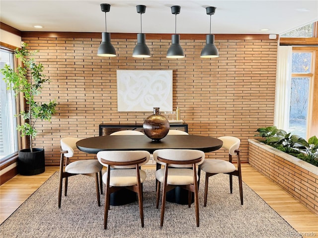 dining space featuring light wood-type flooring and brick wall