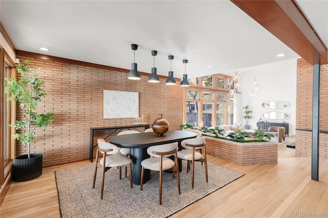 dining room featuring recessed lighting, light wood-style flooring, brick wall, and a fireplace