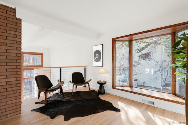 sitting room featuring visible vents, beam ceiling, baseboards, and wood finished floors