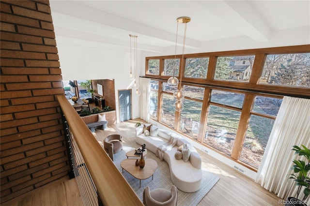 interior space featuring a wealth of natural light, beam ceiling, visible vents, and wood finished floors