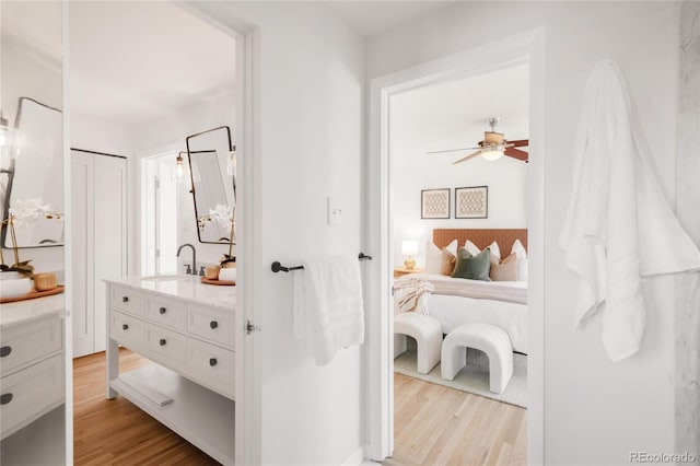 ensuite bathroom with vanity, ensuite bathroom, a ceiling fan, and wood finished floors